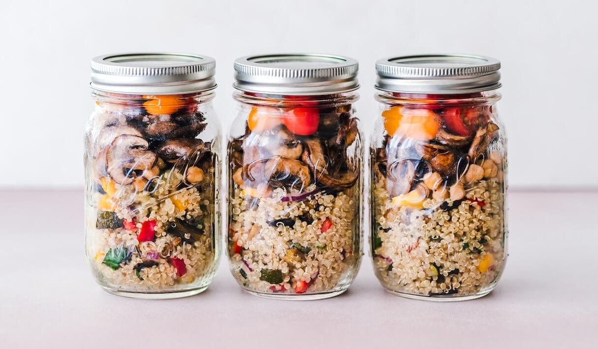 Three visually appealing meal preps in jars, showcasing ingredients layered neatly for a balanced and convenient dining option.